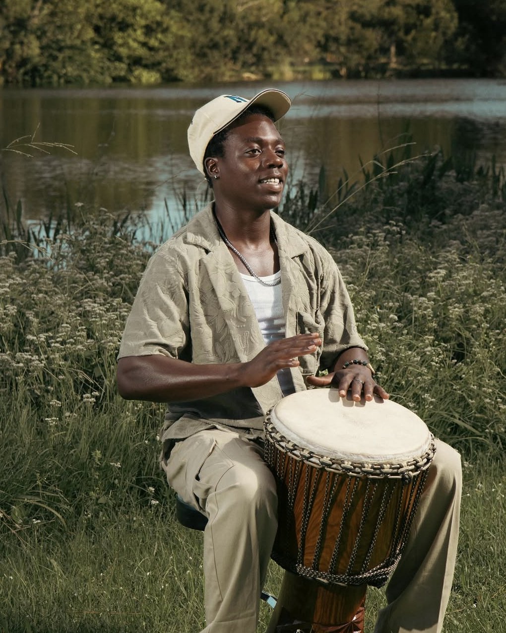 Marc Charlecine seated with his djembe by a lake