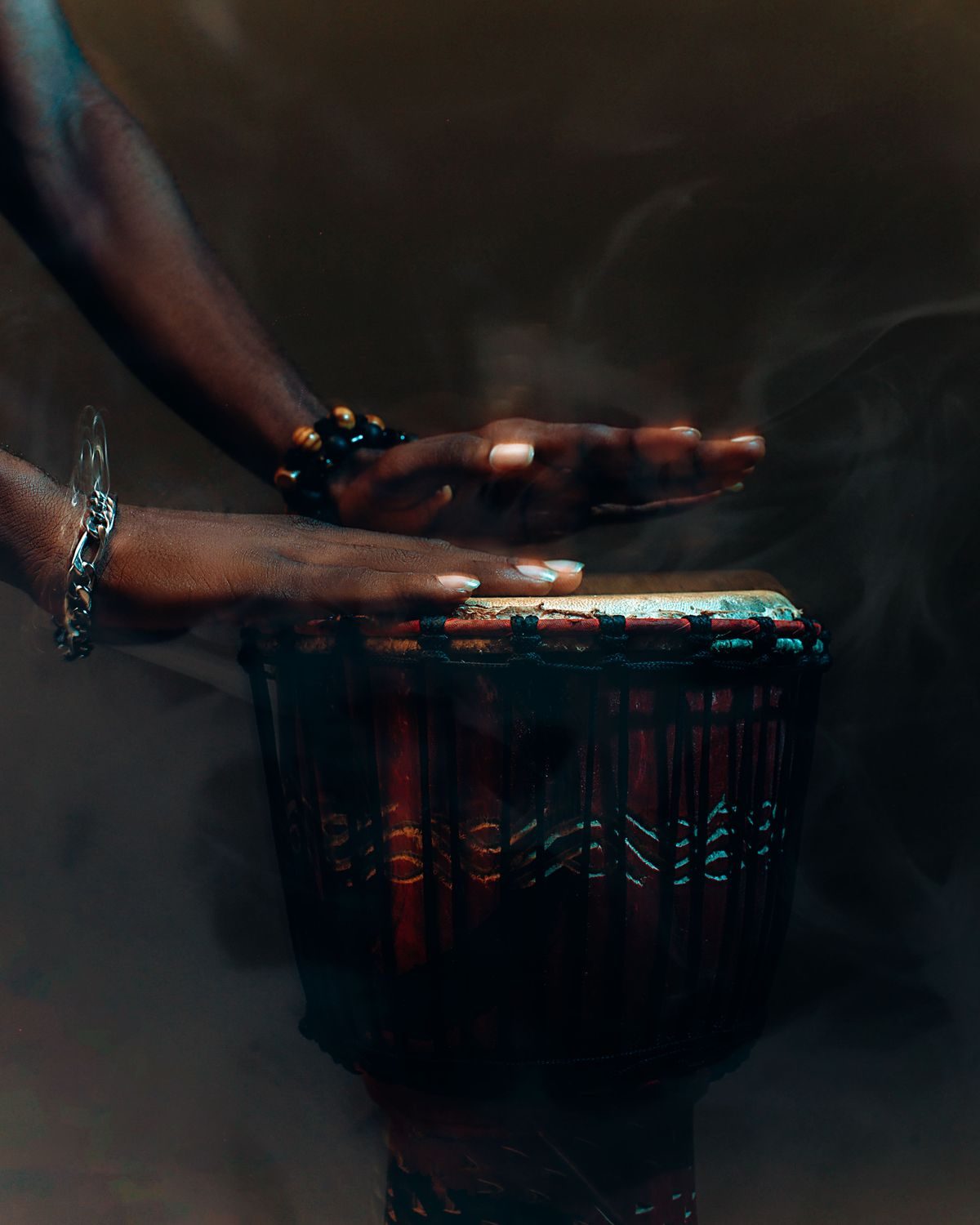 Hands playing a djembe drum